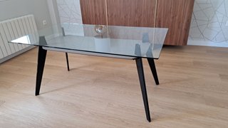 Mesa de cristal moderna con cuatro sillas.