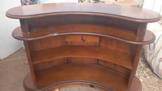 mueble es un bar esquinero de madera con forma cur