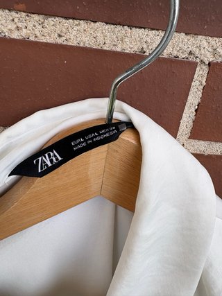 Blusa blanca con volantes y detalle joya
