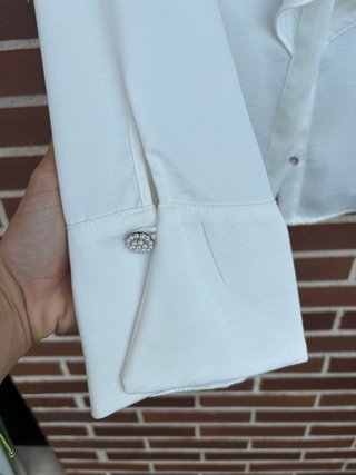 Blusa blanca con volantes y detalle joya
