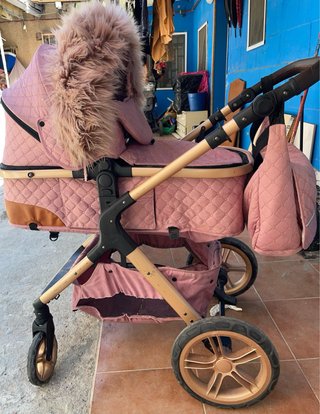 Carro de bebé rosa con capazo y accesorios
