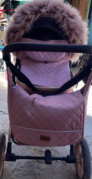 Carro de bebé rosa con capazo y accesorios