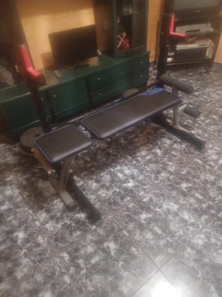 Banco de gimnasio con barras y pesas