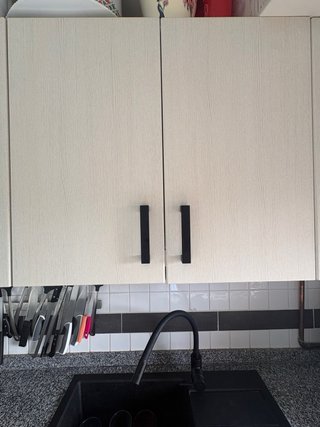 Muebles de cocina beige y negros. Horno y campana