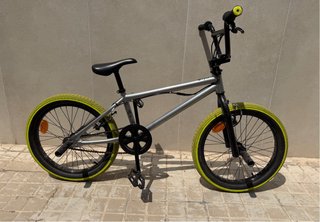 Bicicleta BMX plateada con ruedas amarillas