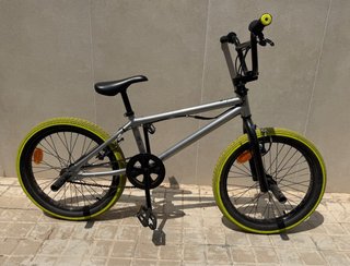 Bicicleta BMX plateada con ruedas amarillas