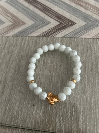 Pulsera de piedras blancas con tortuga dorada