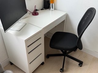 Escritorio blanco con cajón y silla.