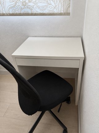 Escritorio blanco con cajón y silla.