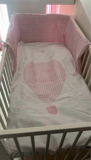Cuna de madera blanca con protector rosa