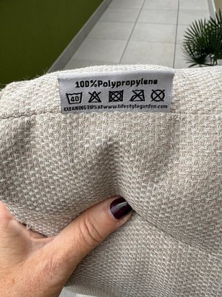 Sofá de terraza beige con cojines y mesa auxiliar