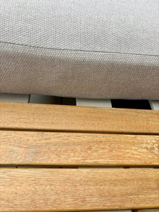 Sofá de terraza beige con cojines y mesa auxiliar