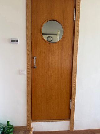 Puerta de madera oscilante con ventana redonda