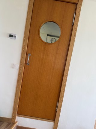 Puerta de madera oscilante con ventana redonda