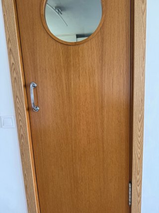 Puerta de madera oscilante con ventana redonda