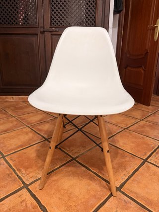 Silla blanca con patas de madera.