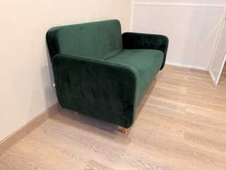 Sofá verde de terciopelo con cojines.
