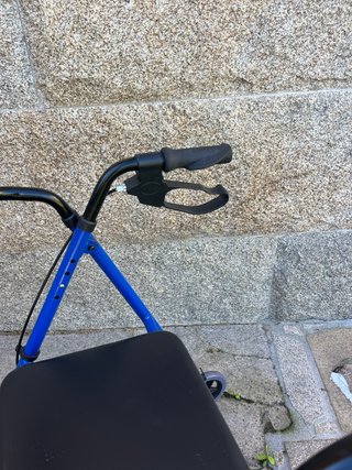 Andador azul con asiento y bolsa. Tiene frenos.