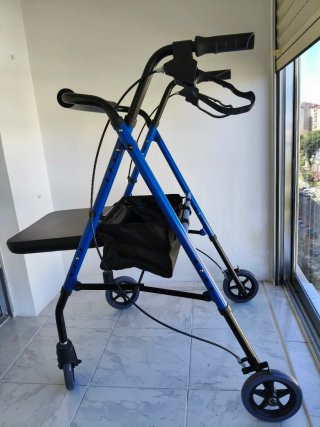 Andador azul con asiento y bolsa. Tiene frenos.
