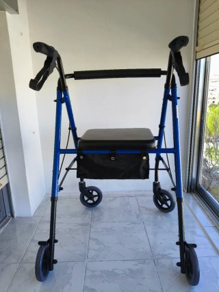 Andador azul con asiento y bolsa. Tiene frenos.