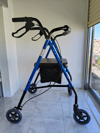 Andador azul con asiento y bolsa. Tiene frenos.