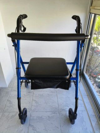 Andador azul con asiento y bolsa. Tiene frenos.