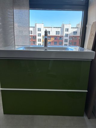 Mueble de baño verde con lavabo y grifo