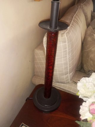 Lámpara de mesa con pie de metal y labrado.