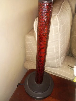 Lámpara de mesa con pie de metal y labrado.