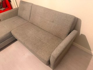 Sofá cama gris con cojines rojos