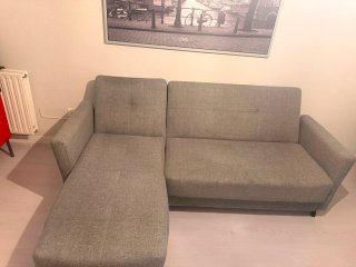 Sofá cama gris con cojines rojos