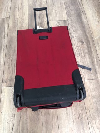 Maleta de viaje roja con ruedas, con daño en tela