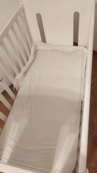 Cuna de bebé blanca con colchón.