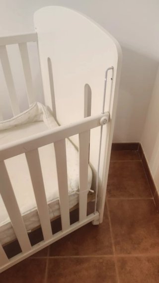 Cuna de bebé blanca con colchón.