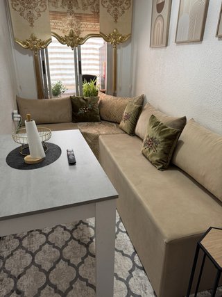 Sofá árabe beige con mesa auxiliar y cortina y