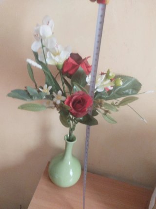 Jarrón verde con flores artificiales rojas