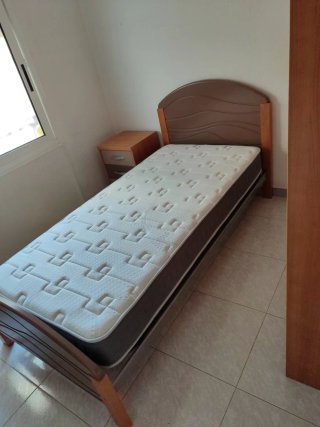 Cama individual, mesita y colchón.