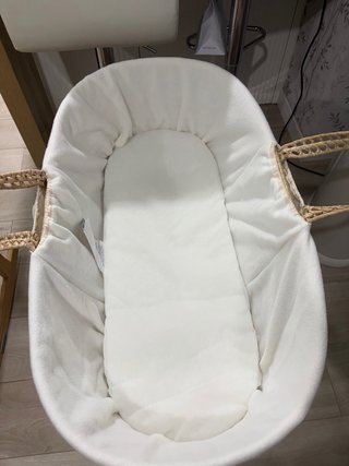 Capazo de mimbre con colchoneta y patas mecedoras.
