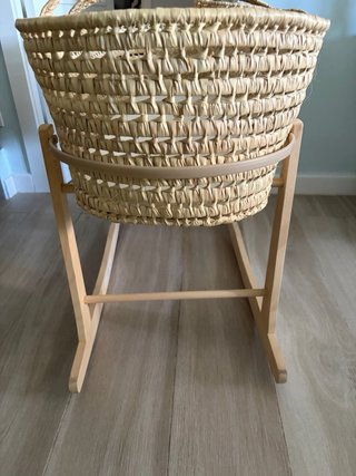 Capazo de mimbre con colchoneta y patas mecedoras.