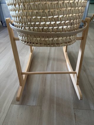 Capazo de mimbre con colchoneta y patas mecedoras.