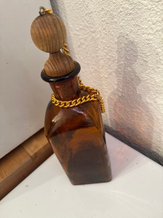 Botella de vidrio ámbar con cadena dorada