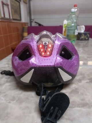 Casco de bici plateado y rosa con luz roja.