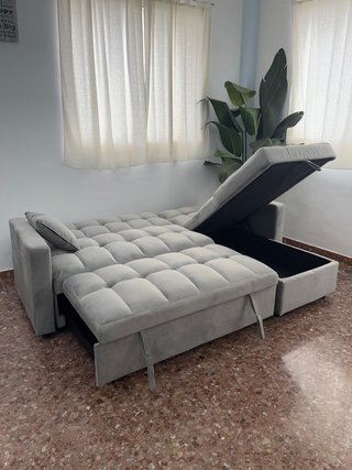 Sofá gris con chaise longue, cama y arcon