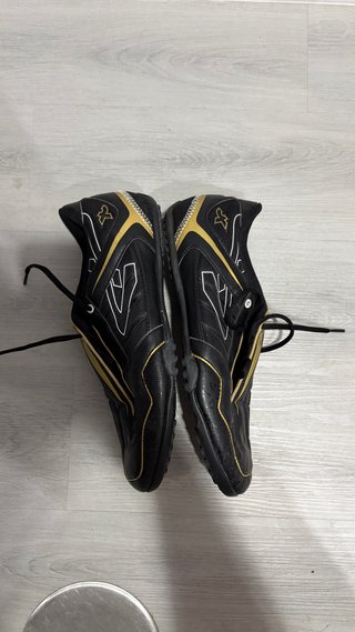 Botas de fútbol multitaco negras y doradas