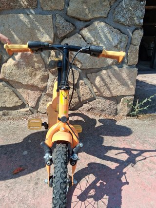 Bicicleta infantil naranja con ruedines