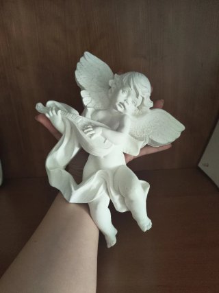 Ángel de escayola con instrumento.