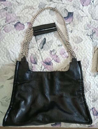 Bolso negro de piel con cadena.