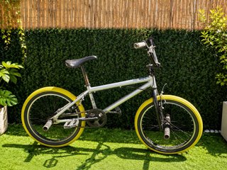 Bicicleta BMX plateada con ruedas amarillas