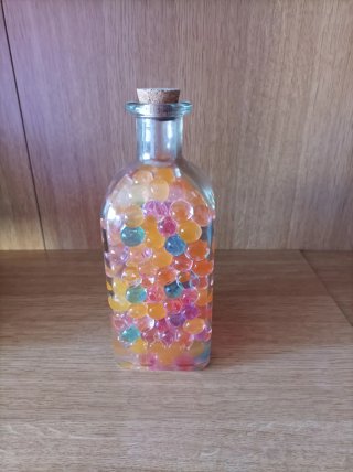 Botella decorativa con bolitas de colores y agua .