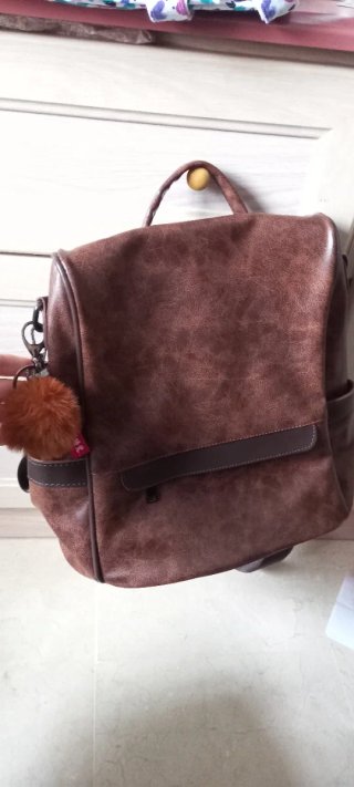 Mochila de piel marrón con pompón naranja